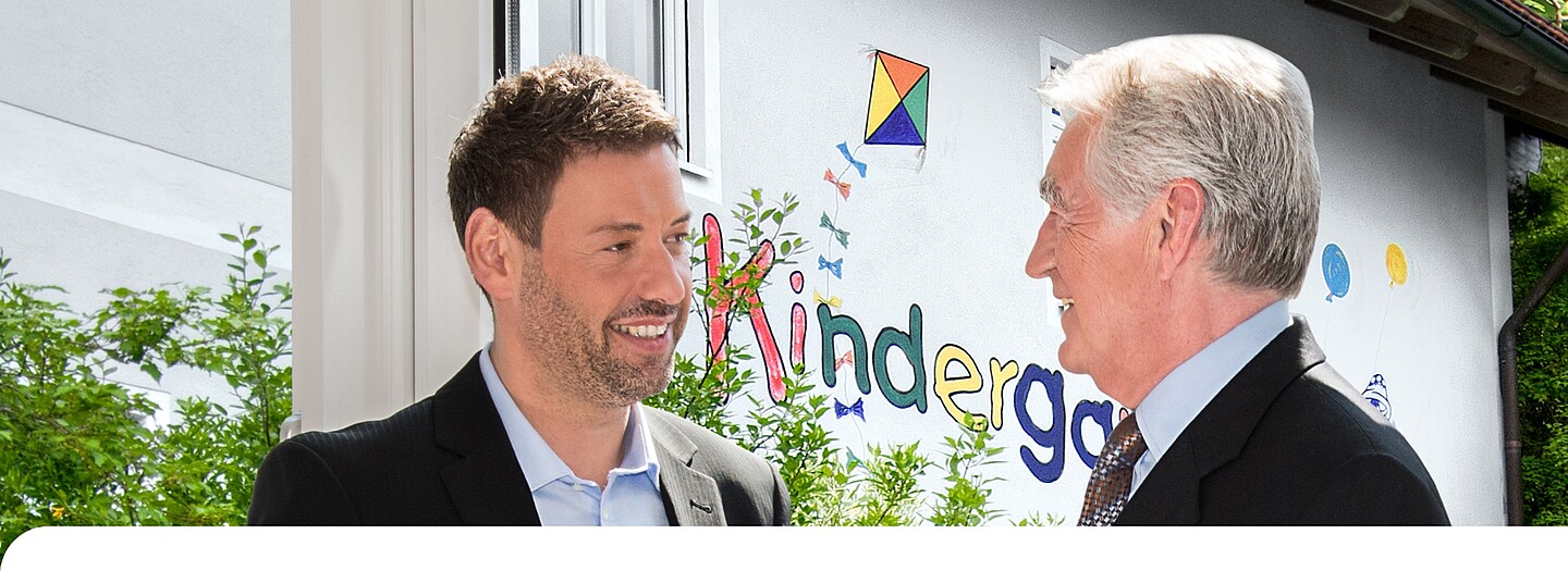 Investkredit Kommunal Bayern der BayernLabo Beratung eines kommunalen Entscheidungsträgers zu Investkredit der BayernLabo vor Kindergarten.