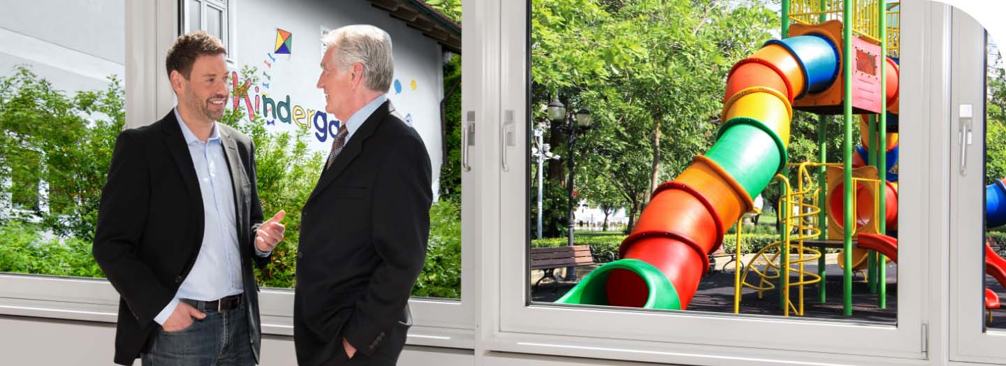 Wachstumhilfe für Ihre Kommune mit dem Investkredit der BayernLabo Beratung eines kommunalen Entscheidungsträgers zu Investkredit der BayernLabo vor Kindergarten.